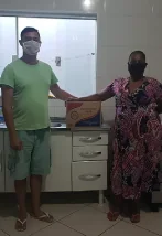 Voluntario de Se Mudando entregando una canasta de alimentos en la casa de la familia acompañada.